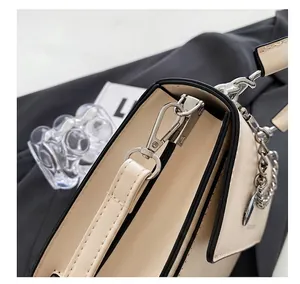 Detail der silbernen Metallbeschläge und des cremefarbenen Lederriemens der Handtasche
