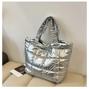 Detail of silver quilted puffer tote bag with stylish ruffled handles and metallic finish