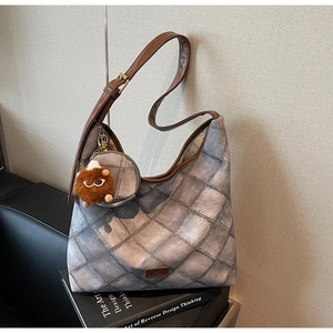 Detail of retro grey quilted Hobo bag with brown leather straps and plush toy charm