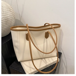 Artistic detail of cream beige tote bag with brown handles on a minimalist prop display