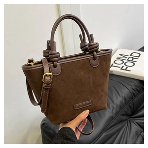 Dettaglio di una borsa tote in pelle scamosciata marrone scuro con finiture in pelle e nodi decorativi