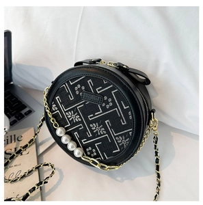 Detail of black round crossbody bag with floral embroidery and large pearl chain decoration