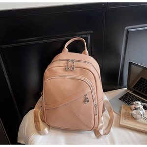 Detailed view of pink pebble grain leather backpack with silver zippers and side pockets