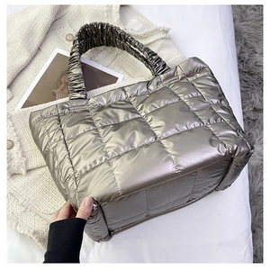Detail of silver metallic quilted tote bag with puffer texture and ruffled handles