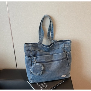 Detail of a large denim tote bag featuring multi-pocket design and removable round coin purse