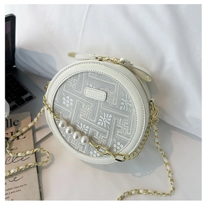 Detail of white round crossbody bag featuring floral jacquard, pearls, and gold chain strap