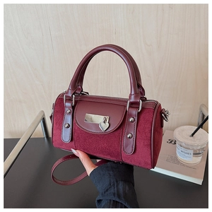 Détail du sac boston en cuir bordeaux et daim avec pendentif coeur et garniture métal