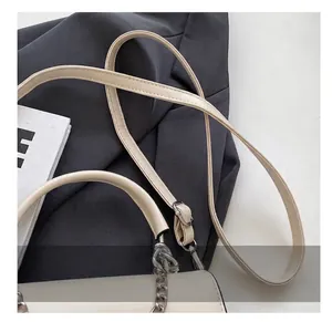 Detailaufnahme der cremefarbenen Ledertasche mit verstellbarem Gurt und Kettengriff