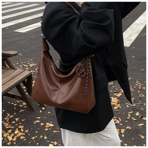 Detail of vintage dark brown leather hobo bag with braided tassel and knot strap