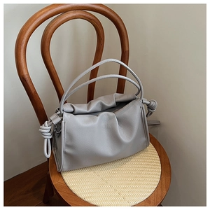 Detail der grauen gefalteten Cloud-Bag mit Knotengriff auf einem Vintage-Stuhl