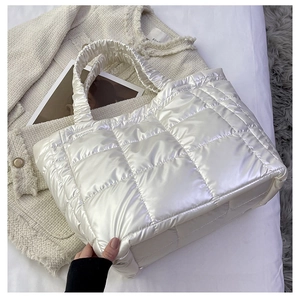 Detailed view of white quilted puffy tote bag with glossy finish and padded handles