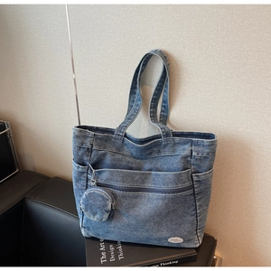 Detail of blue denim tote bag with circular coin purse and white 'good luck' patch