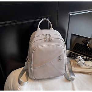 Detailed view of grey textured leather backpack with silver hardware and woven straps