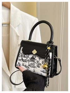 Detailed view of women's contrast handbag with ink landscape print and gold clover clasp