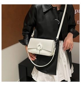 Detail of white quilted crossbody bag with metal buckle on black leather jacket