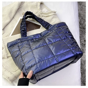 Detail of navy blue quilted tote bag featuring metallic finish and ruched handle
