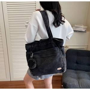 Close-up of black washed denim tote bag with round pendant and good luck leather label