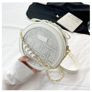 Detail of round crossbody bag with floral embroidery and large pearls on gold chain
