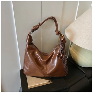 Detail of dark brown leather hobo bag with knotted shoulder strap and gold ring