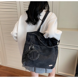 Close-up of black washed denim tote bag with functional zippers and small round pouch