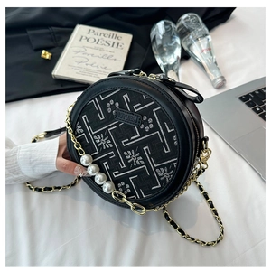 Detail of black round crossbody bag with floral embroidery and pearl chain accessories