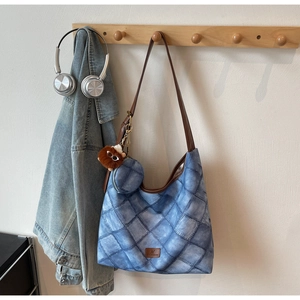 Quilted blue hobo bag with brown leather strap and mini coin purse charm on a rack