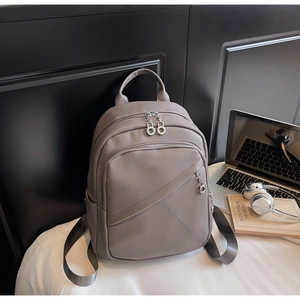 Detail of taupe pebbled leather backpack with silver zippers and side chain accents