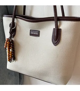 Close-up of canvas tote bag showing leather edges and colorful wooden bead tassel