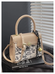 Detail of color-block satchel with landscape canvas, gold floral clasp and woven charm