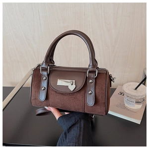 Gros plan d'un sac Boston vintage en daim marron avec pendentif cœur argenté