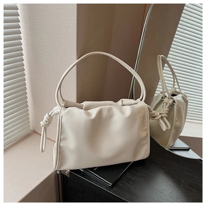 Detailaufnahme der cremeweißen Cloud Bag mit gerafftem Leder und seitlichen Knotendetails