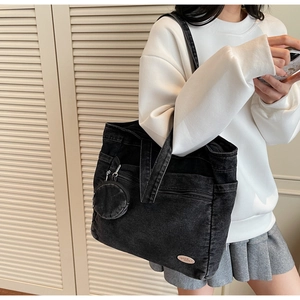 Close-up of black denim tote bag with mini coin purse and pink good luck patch detail