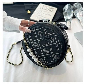 Detail of round crossbody bag with geometric embroidery and elegant pearl chain strap
