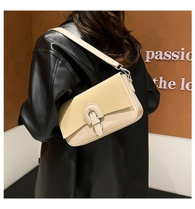 Detail of cream beige baguette bag with suede flap shown on model in leather jacket