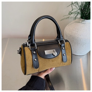 Détail du sac seau rétro en daim moutarde avec bordures en cuir et pendentif en cœur