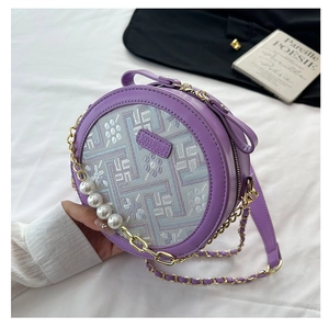 Detail view of purple round crossbody bag featuring floral embroidery and pearl chain strap