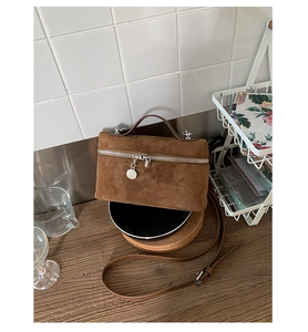 Detail of a brown suede small square bag with silver metal zipper and adjustable strap