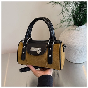 Détail du sac seau en daim jaune moutarde avec bordure en cuir noir et breloque coeur