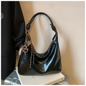 Detail of black glossy hobo bag with knotted strap and unique abacus charm ornament