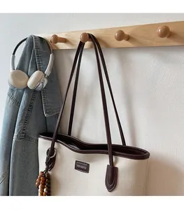 Detail of canvas tote bag with brown leather trim and decorative wooden beads