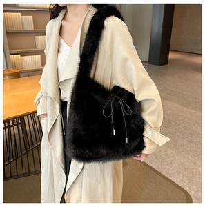 Détail d'un sac à bandoulière en fausse fourrure noire avec nœud décoratif en cuir
