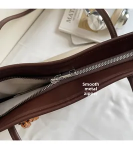 Close-up of smooth silver metal zipper and chevron lining on dark brown tote bag
