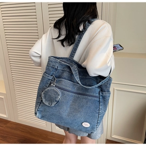 Detail of blue denim tote bag with circular coin purse and Good Luck text embroidery