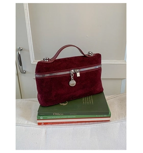 Macro shot of burgundy faux suede handbag with silver studs and zipper detail on books