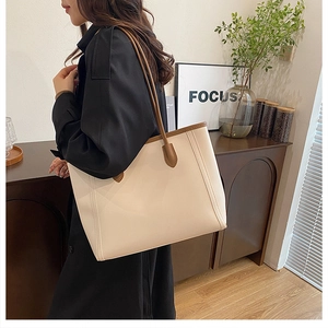 Detail of minimalist tote bag in cream and brown leather on a rustic wooden cabinet
