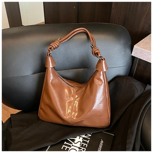 Detail of knotted shoulder strap on brown vintage leather hobo bag with matte finish