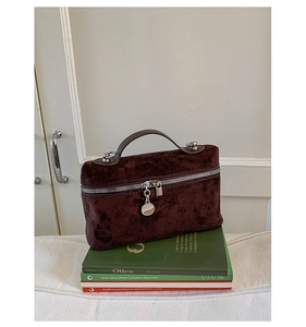 Detail of dark brown suede handbag with silver double zippers and metal charms