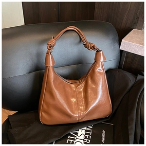 Detailed view of the knotted handle design and caramel leather texture of the shoulder bag