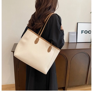Detail view of large faux leather tote bag in beige with slim brown shoulder straps