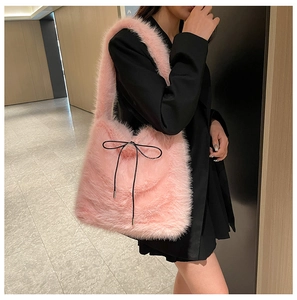 Détail du sac cabas en peluche rose avec nœud noir porté par un mannequin en noir